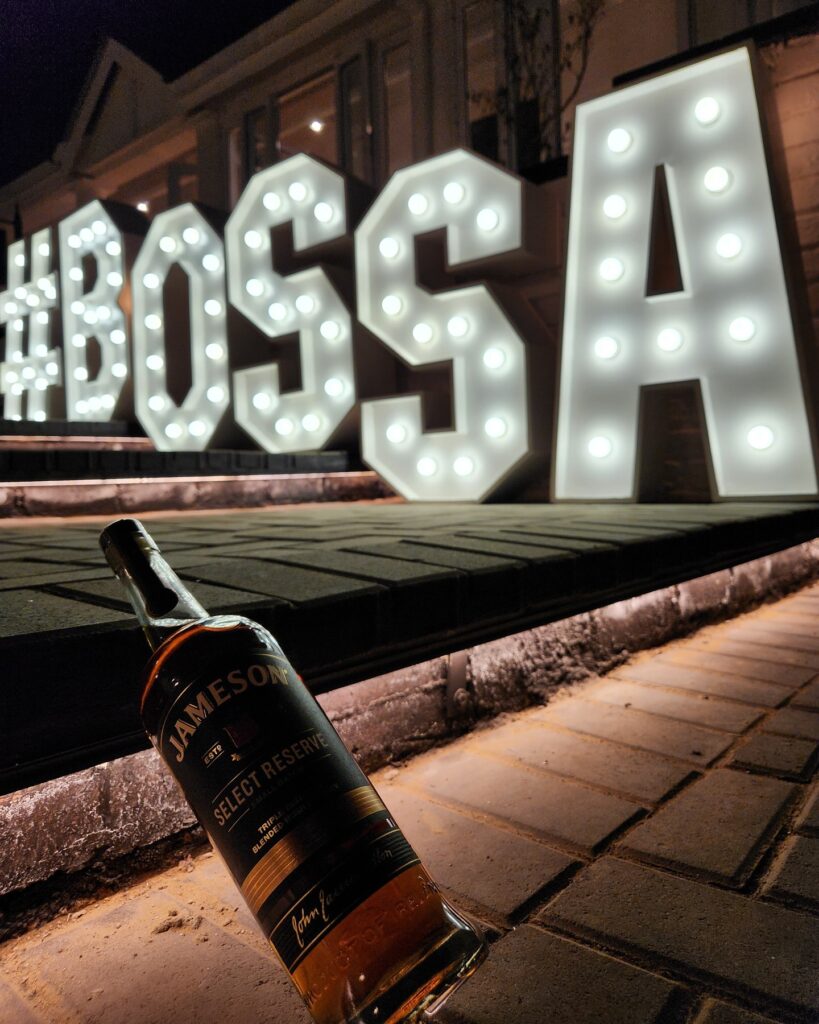 A bottle of Bossa Bossa whisky displayed elegantly on a wooden surface, highlighting its rich amber color and label design.